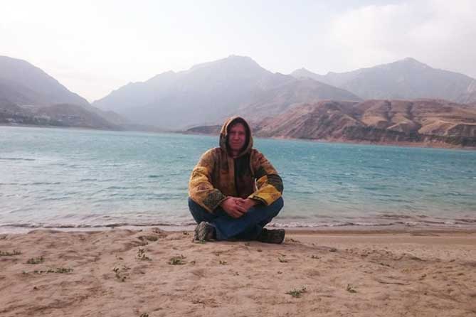 мужчина сидит на берегу озера в Узбекистане