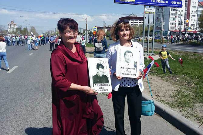 участницы шествия держат в руках фотографии погибших в войне