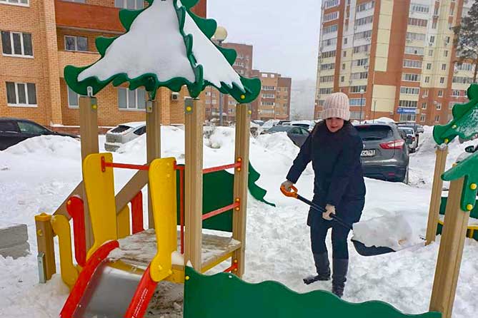 убирают снег во дворе на детской площадке
