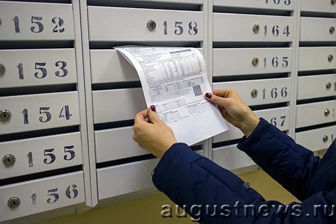 женщина достает счет за квартиру из почтового ящика