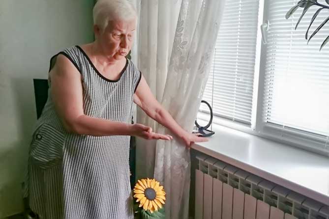 женщина показывает на бетареи в квартире после капремонта