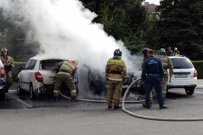 пожарный тушит горящий автомобиль